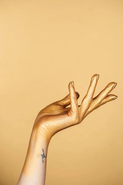 Cropped view of female painted hand with tattoo isolated on gold — Stock Photo