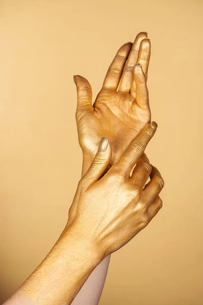 Vista recortada de manos pintadas femeninas aisladas en oro - foto de stock