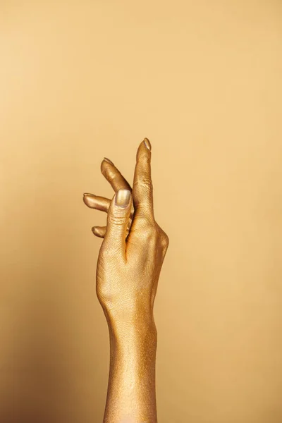 Vista recortada de la mano pintada femenina sobre fondo dorado con espacio de copia - foto de stock