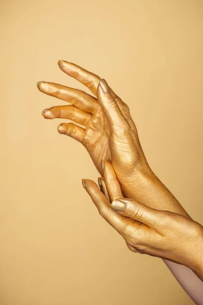Vista parcial de las manos pintadas femeninas aisladas en oro - foto de stock