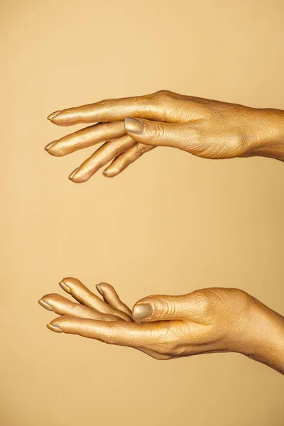 Обрізаний вид жіночих розфарбованих рук ізольовані на золоті — стокове фото