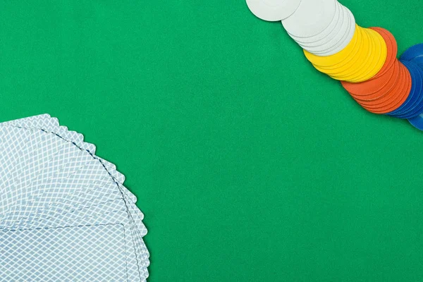 Top view of green poker table with multicolored chips and unfolded playing cards — Stock Photo