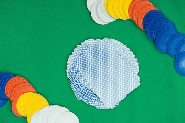 Top view of green poker table with multicolored chips and playing cards — Stock Photo
