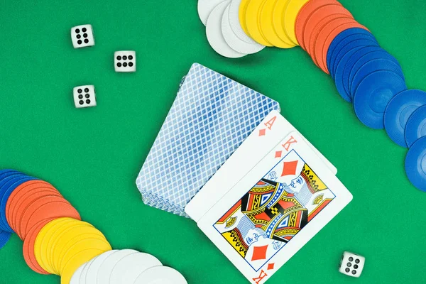 Top view of green poker table and multicolored chips, dices, playing cards with diamonds suit — Stock Photo