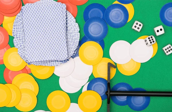 Top view of green poker table with multicolored chips, playing cards, dices and stick — Stock Photo