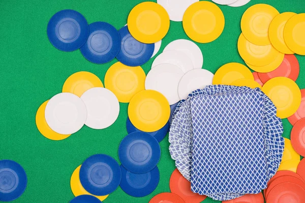 Top view of green poker table with multicolored chips and playing cards — Stock Photo