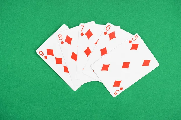 Top view of green poker table and unfolded playing cards with diamonds suit — Stock Photo