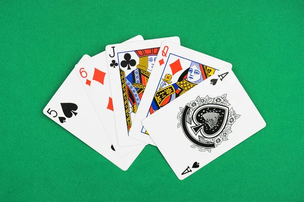 Вид зверху на зелений покерний стіл з розгорнутими гральними картками діамантами, піками та клубними костюмами — стокове фото
