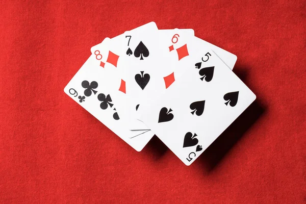 Вид зверху на червоний стіл і розгорнуті ігрові карти з різними костюмами — стокове фото