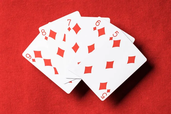 Vista superior de la mesa de póquer rojo y cartas desplegadas con palo de diamantes - foto de stock