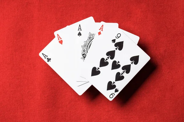 Vista superior de la mesa de póquer rojo con cartas desplegadas, cuatro ases y nueve — Stock Photo