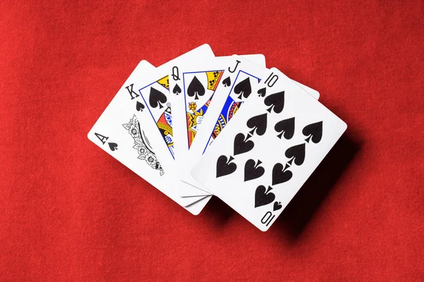 Vista superior de la mesa de póquer rojo y cartas desplegadas con palo de espadas - foto de stock