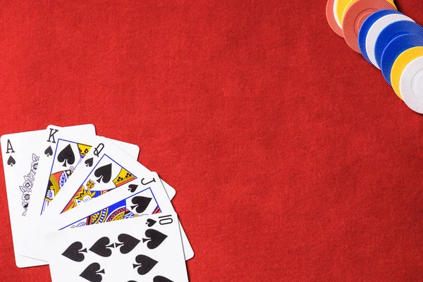 Top view of red poker table with multicolored chips and unfolded playing cards — Stock Photo