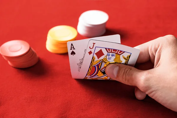 Messa a fuoco selettiva di uomo in possesso di carte da gioco con chip su sfondo — Foto stock
