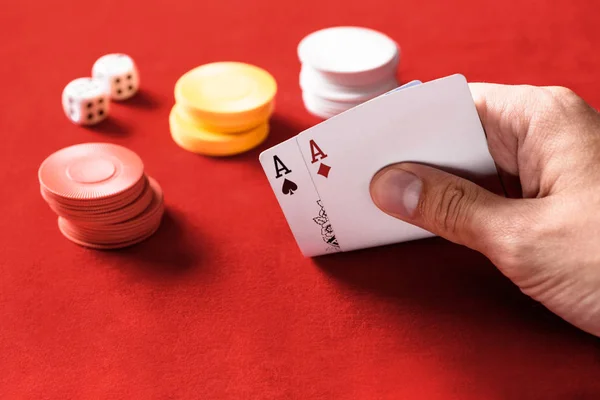 Messa a fuoco selettiva di uomo in possesso di carte da gioco con fiches e dadi su sfondo — Stock Photo