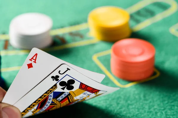 Selective focus of playing cards with chips and green poker table on background — Stock Photo