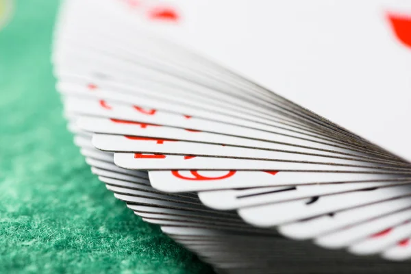 Selective focus of unfolded playing cards in deck on green poker table — Stock Photo