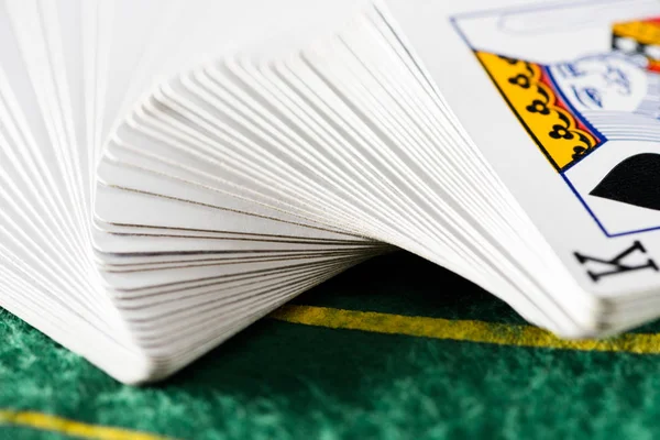 Selective focus of horizontally spread out playing cards in deck on green poker table — Stock Photo