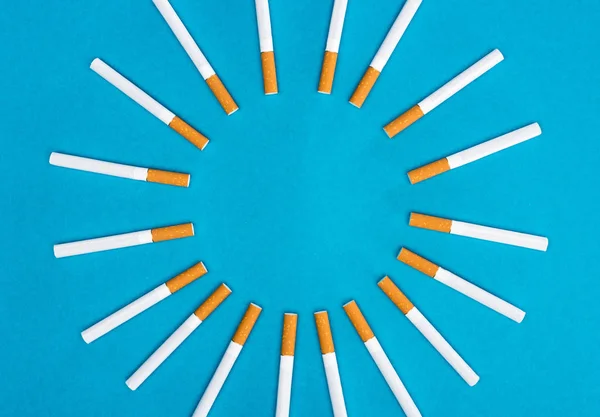 Pose plate avec cigarettes isolées sur bleu — Photo de stock