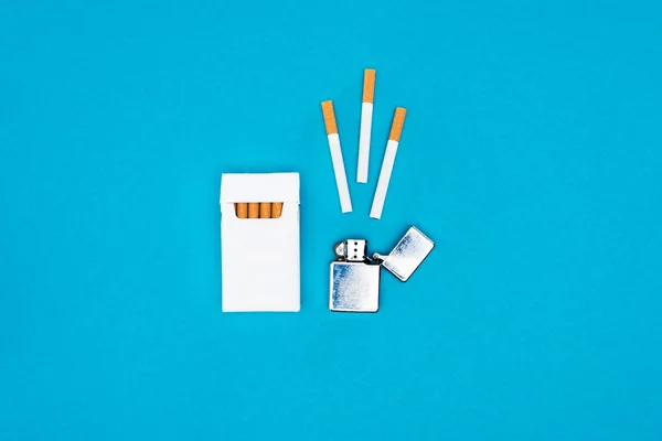 Vue du dessus du paquet de cigarettes blanches et briquet isolé sur bleu — Photo de stock