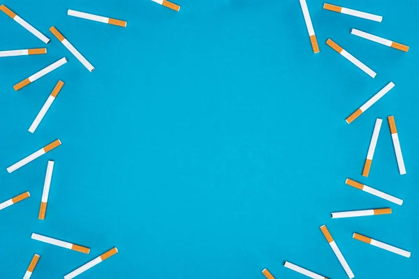 Vista superior de cigarrillos aislados en azul - foto de stock