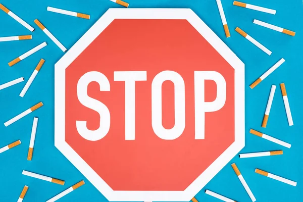 Studio shot of big stop sign with cigarettes isolated on blue, stop smoking concept — Stock Photo