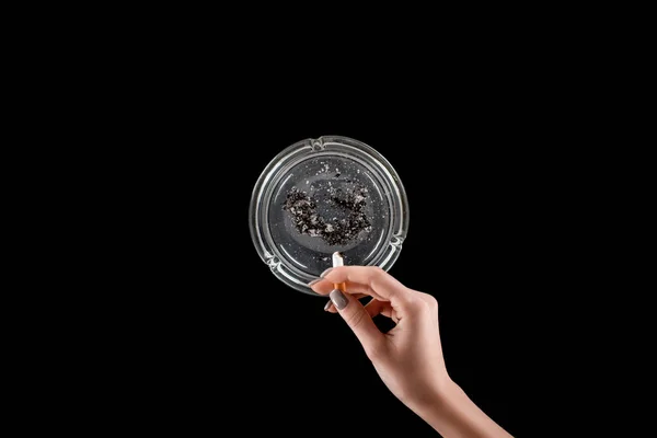 Vue recadrée de la femme avec manucure à l'aide de cendrier en verre isolé sur noir — Photo de stock