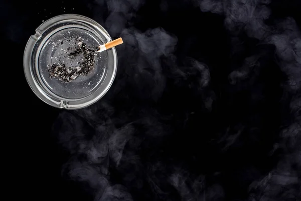 Top view of glass ashtray with ash and cigarette — Stock Photo