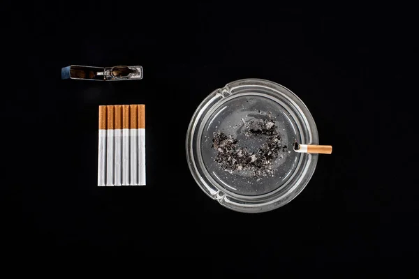 Flat lay with ashtray, cigarettes and lighter isolated on black — Stock Photo