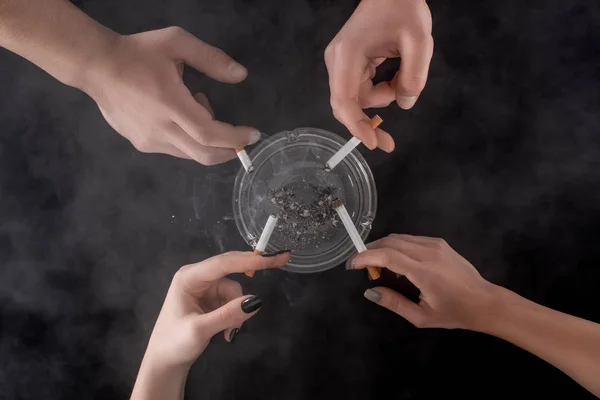 Partial view of smoking people using glass ashtray — Stock Photo
