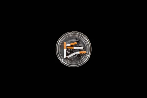 Top view of glass ashtray with ash and cigarettes isolated on black — Stock Photo