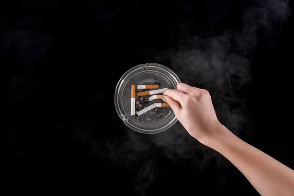 Partial view of smoking woman puts out cigarette in ashtray isolated on black — Stock Photo