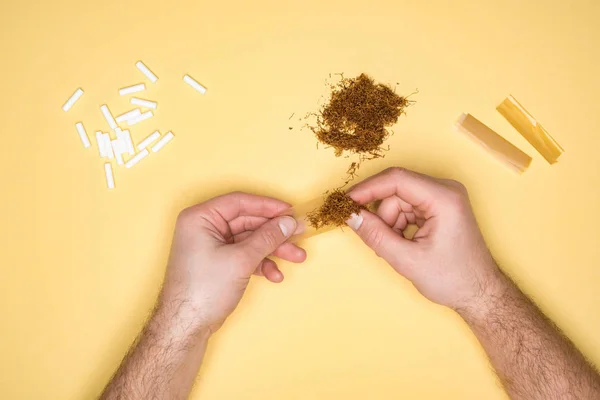Vue partielle du jeune homme qui consomme du tabac isolé sur jaune — Photo de stock