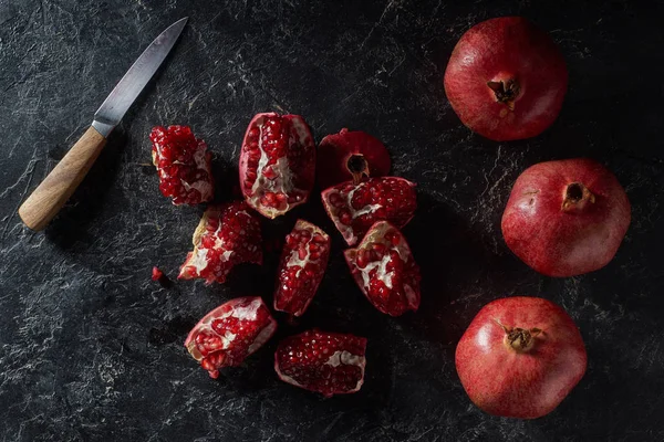 Top view of ripe pomegranates and knife on textured surface — Stock Photo