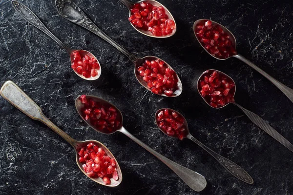 Flache Lage mit Metalllöffeln und Granatkörnern — Stockfoto