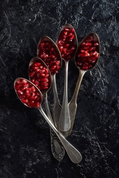 Flat lay with old cutlery and garnet seeds on dark background — Stock Photo