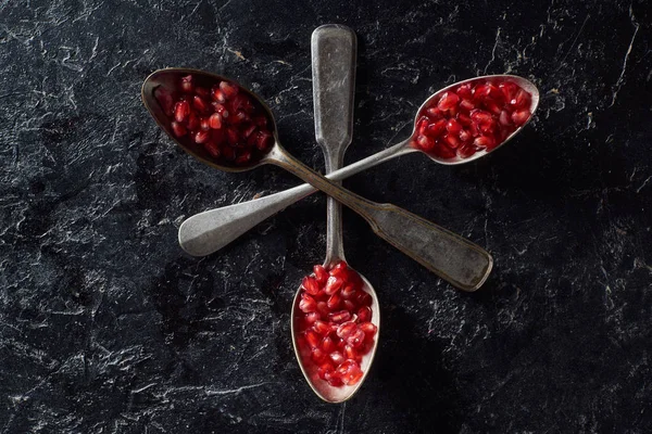 Flat lay with crossed spoons and garnet seeds — Stock Photo