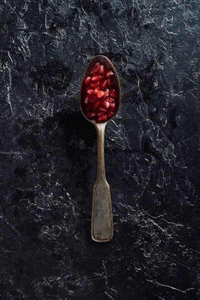 Vista superior da colher vintage com sementes de granada no fundo escuro — Fotografia de Stock