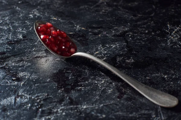 Atelieraufnahme eines Löffels mit Granatkernen auf dunkler Oberfläche — Stockfoto