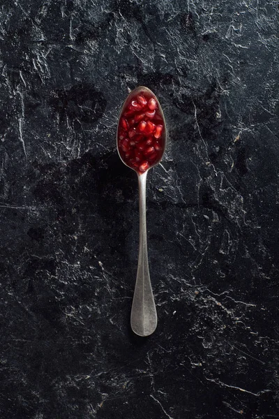 Top view of spoon with pomegranate seeds on dark surface — Stock Photo