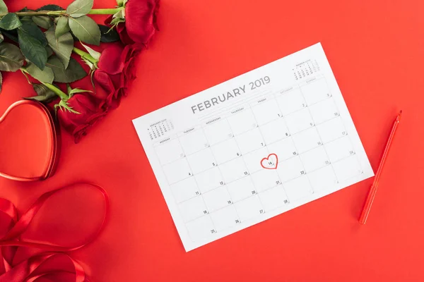 Vista superior de rosas y calendario con fecha 14 de febrero marcada con corazón aislado en rojo, concepto de San Valentín - foto de stock