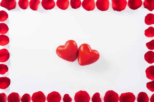 Вид зверху квіткової рамки, зробленої з пелюсток червоної троянди та сердець ізольовані на білому, концепція дня Святого Валентина — стокове фото