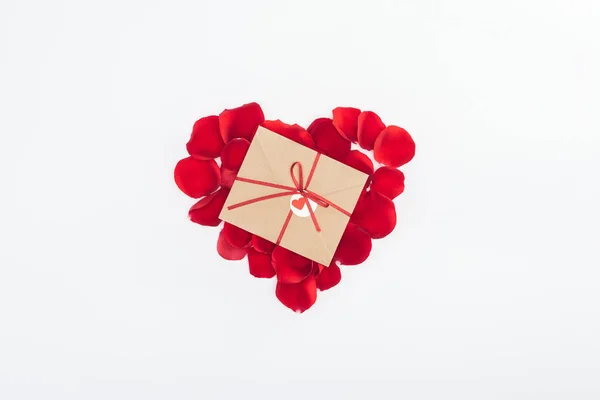 Вид зверху конверт зі стрічкою та серцем з пелюсток червоної троянди ізольовані на білому, концепція дня Святого Валентина — стокове фото