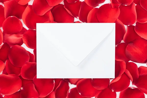 Top view of envelope with copy space and red rose petals on background — Stock Photo