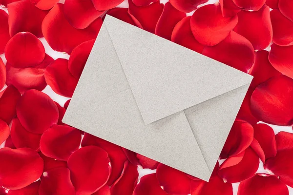 Top view of envelope with copy space and red rose petals on background — Stock Photo