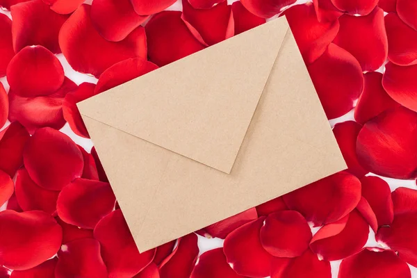 Vue du dessus de l'enveloppe avec des pétales de rose rouge sur le fond — Photo de stock