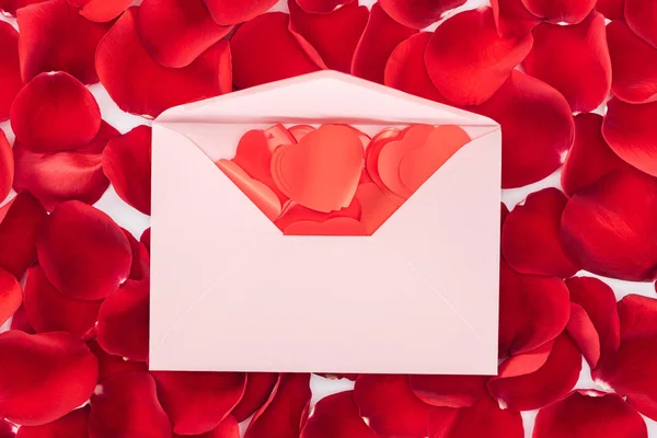 Vista superior del sobre con confeti en forma de corazón y pétalos de rosa roja en el fondo, San Valentín concepto de día - foto de stock