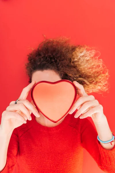 Vue du haut de la fille tenant le symbole du cœur devant le visage isolé sur le rouge, st concept de la Saint-Valentin — Photo de stock