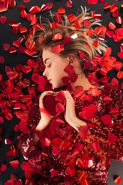 Вид зверху красивої дівчини, що тримає символ серця у формі серця, конфетті ізольовано на чорному, концепція дня святого Валентина — стокове фото