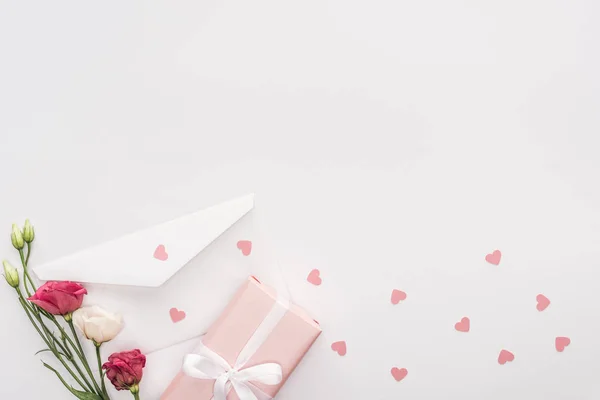 Vue du dessus de coffret cadeau, fleurs, enveloppe et coeurs en papier isolés sur blanc — Photo de stock